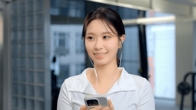 Young woman using smartphone with earphones at gym