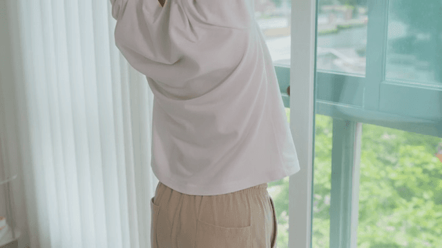 Person Stretching by a Window Overlooking Greenery