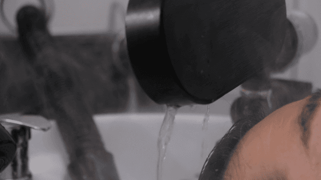 Person washing hair with water at beauty salon