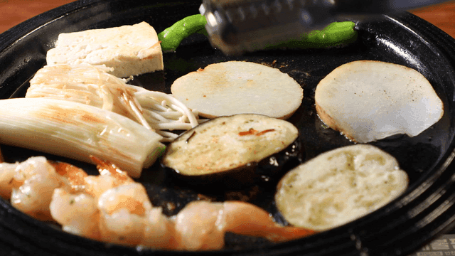 Various ingredients grilling on a hot plate