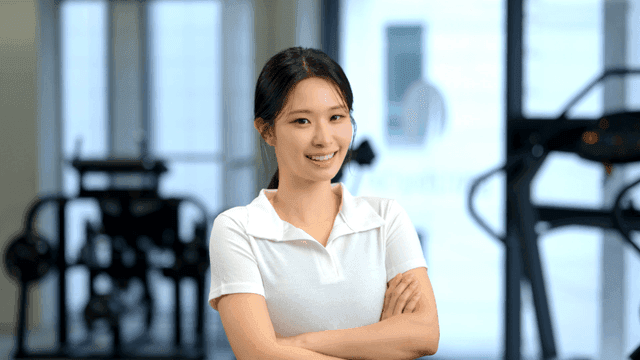 체육관에서 자신감 있게 정면을 보고 미소 짓는 여성