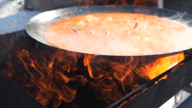 Chicken stew in large pot lid boiling over fire