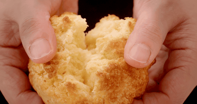 손으로 반으로 갈라지는 잘 구워진 스콘빵