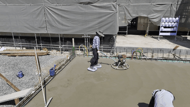 Workers smoothing concrete at a construction site
