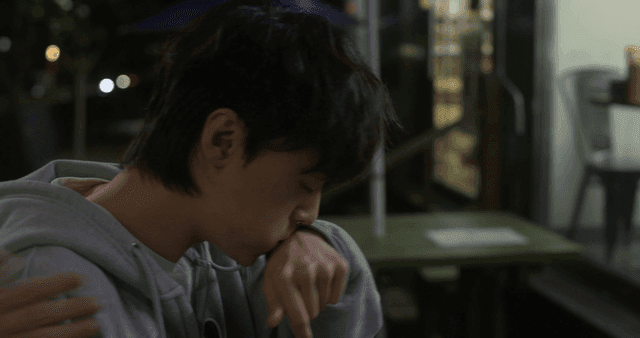 Young man looking back at night with his mouth full of food