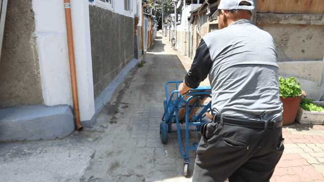 Elderly man pushing a cart down an alley