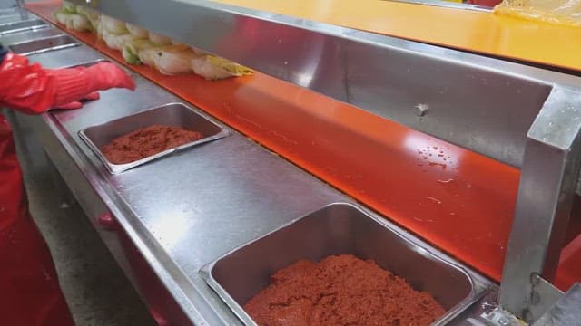 Making kimchi by adding chili pepper seasoning to cabbage