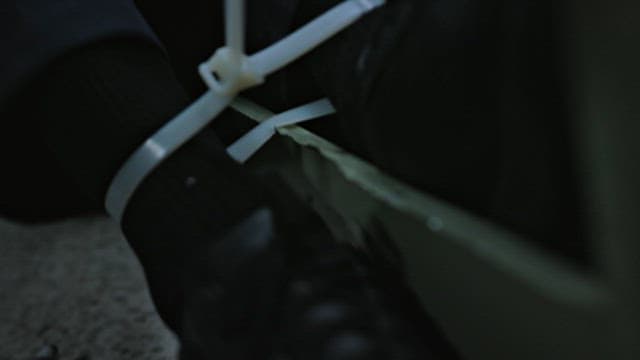 Person Struggling to Loosen the Cable Ties Binding his Feet