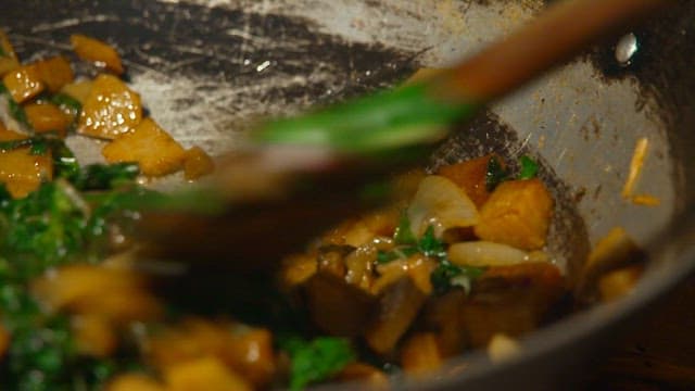 야외 불 위 프라이팬에서 시금치와 참치를 볶아 만드는 요리