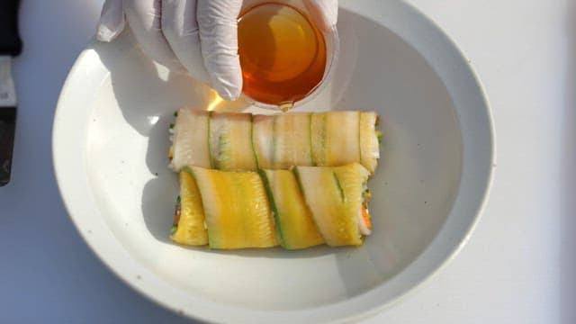 Pouring Sauce onto Rolled Cucumber Dish in a Plate