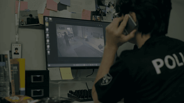 Man receiving a phone call while watching security footage on monitor