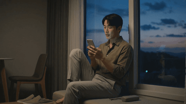 Man sitting by window looking at his smartphone