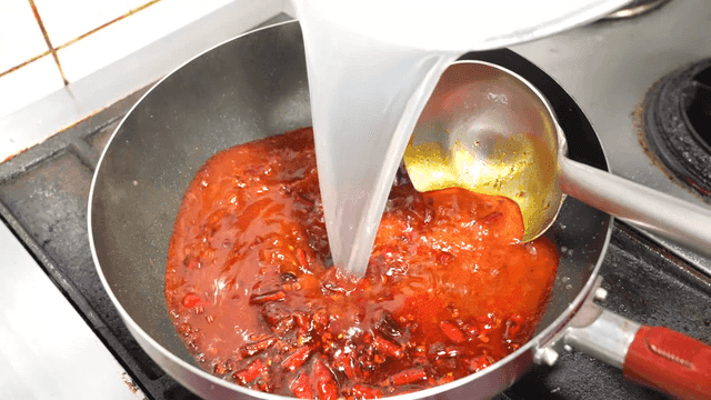 White broth poured over spicy mala sauce