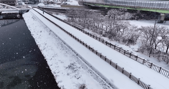 Snowy riverside path with a lone walker