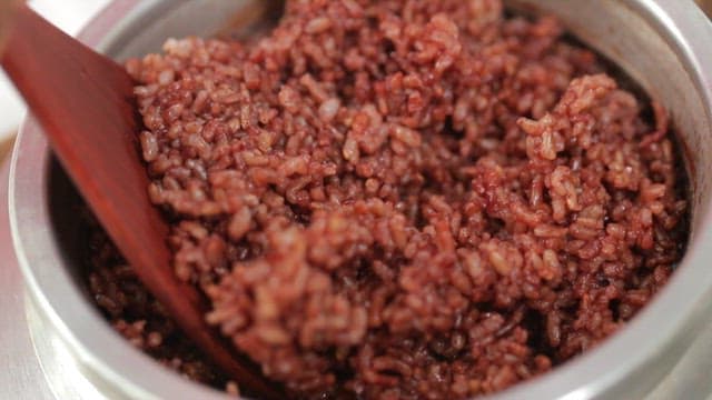 Stirring cooked brown rice with a wooden spatula