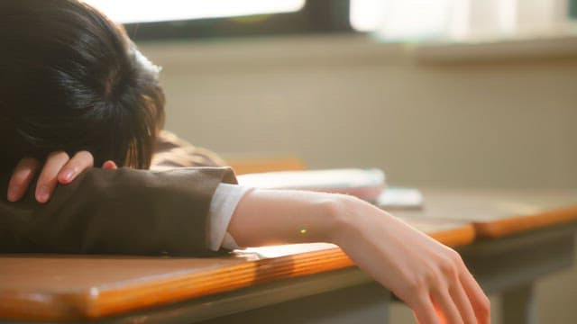 Student resting on a desk in a classroom