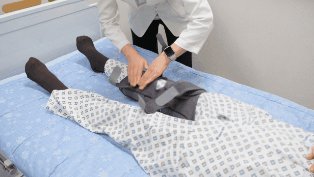 Doctor adjusts patient's leg brace.