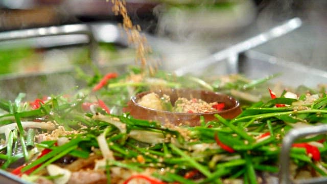 Sprinkling sesame seeds on top of stir-fried white sundae with chives