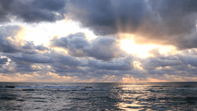 Cloudy sky over a calm ocean at sunset