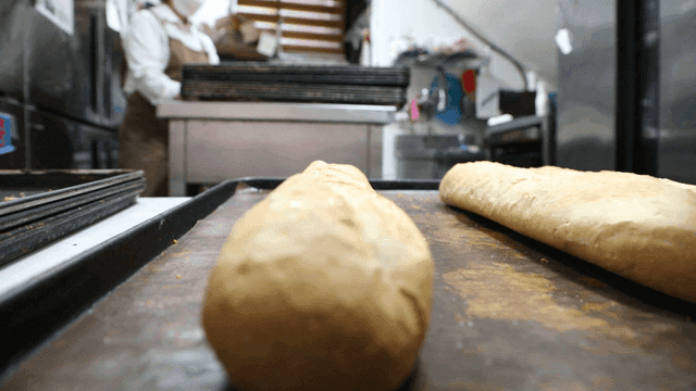 Baker brushing glaze on bread on a tray