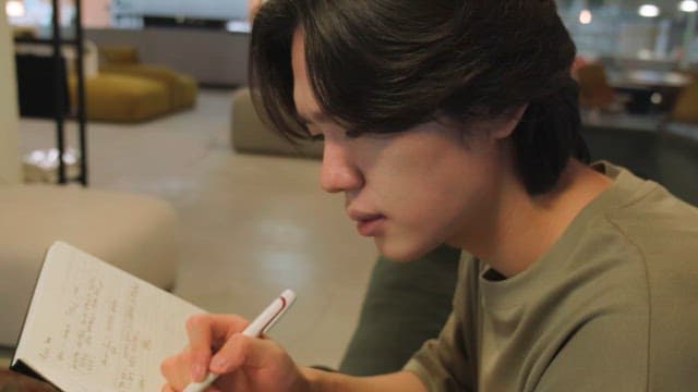 Young man writing in a notebook indoors