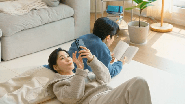 Couple relaxing at home with a book and phone