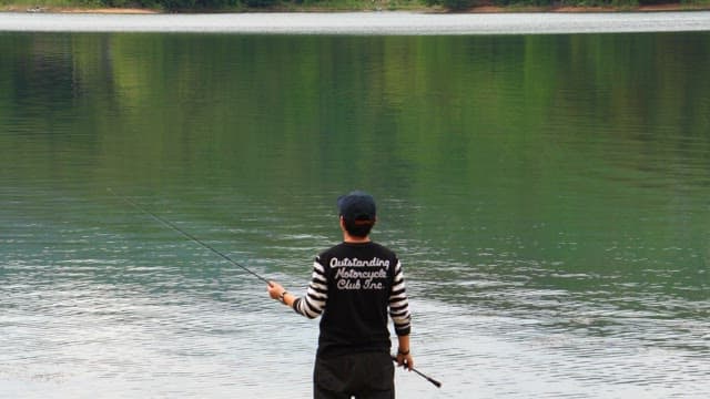 흐린 날 고요한 호숫가에서 낚시하는 사람