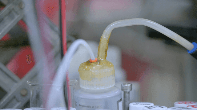 Sample bottle connected to chemical hose in laboratory equipment