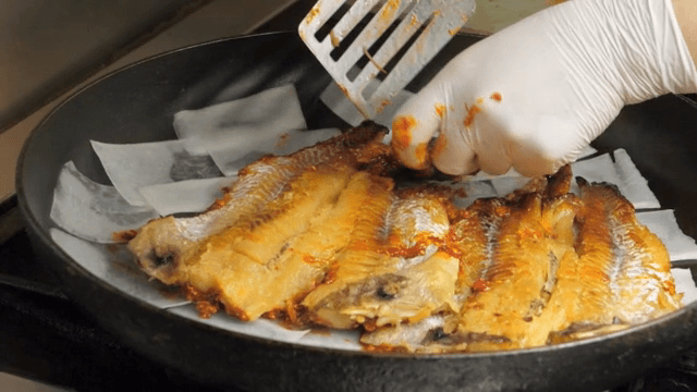 Fish being seasoned and cooked in a pan