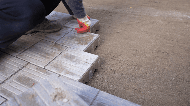 Worker laying bricks on a sandy surface