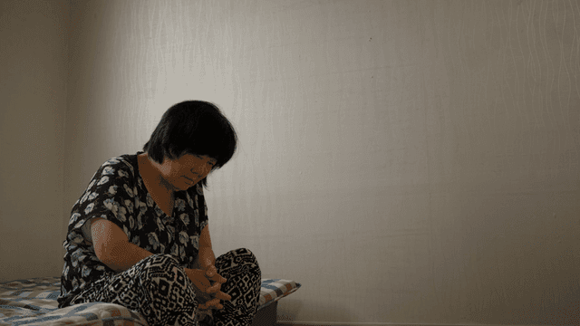 An elderly woman sitting on a bed