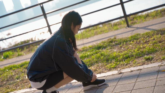 Woman tying her shoelaces by the river