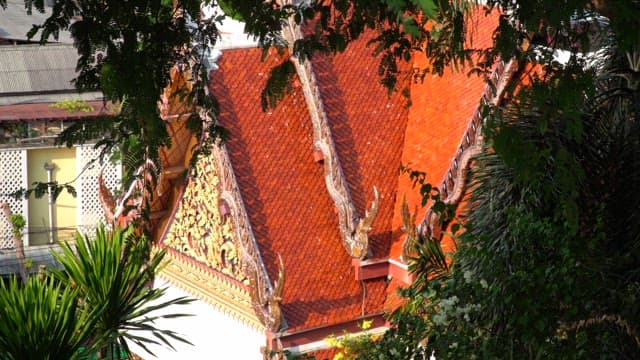 Ornate Thai temple roof surrounded by foliage