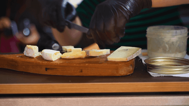 Cheese being sliced on a wooden board