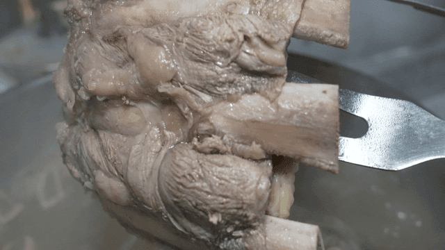 Boiled meat being lifted with tongs