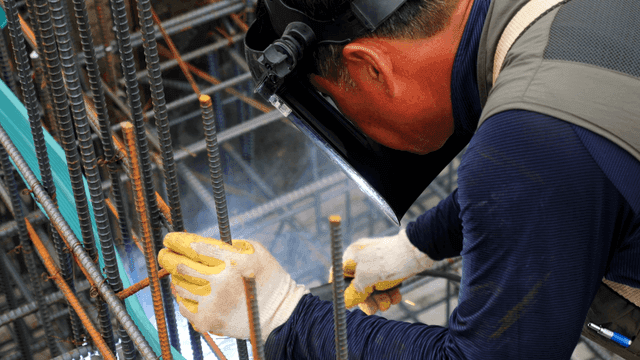 Worker welding metal bars at a construction site
