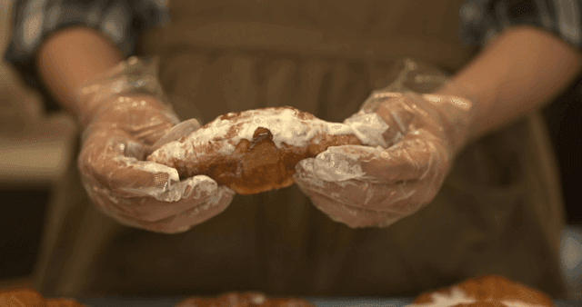 Hands touching pastry heavily coated with cream