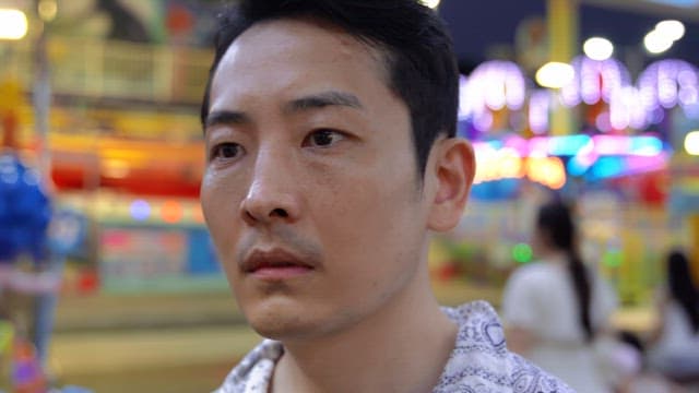밤에 화려한 놀이공원에 있는 남자