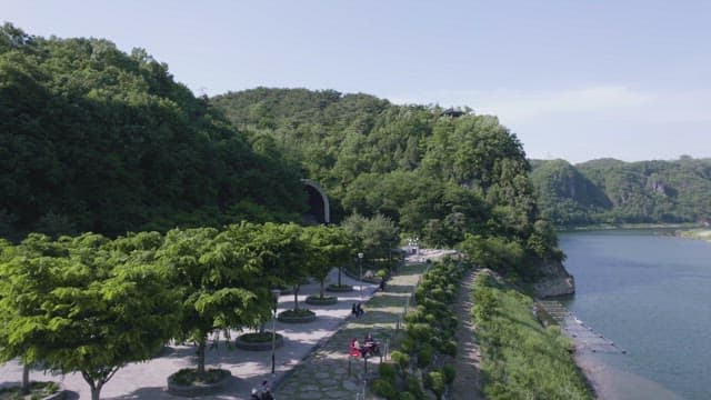 옆에 나무가 많은 언덕이 있는 강변 공원의 풍경