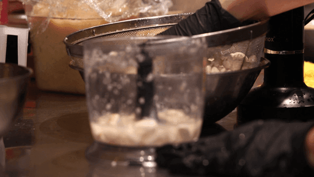 Hand filling blender with garlic