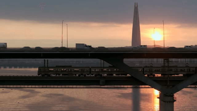 Train passing under a busy city bridge
