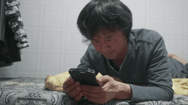 Man lying in bed talking on smartphone