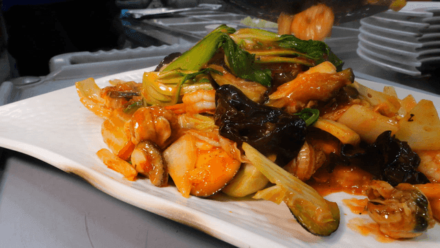 Stir-fried red scallops with seafood and vegetables on plate
