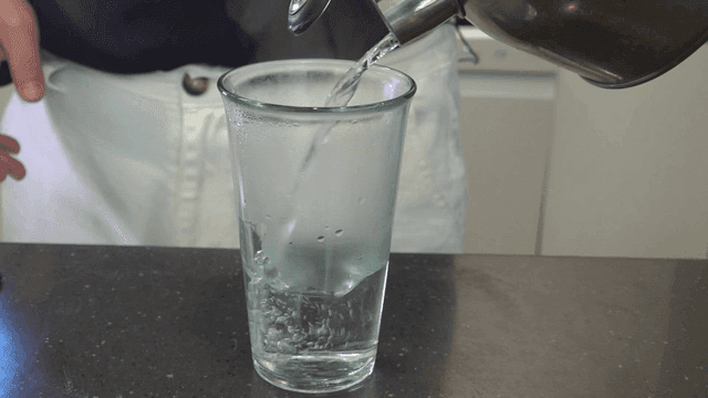 Person pouring hot water into glass
