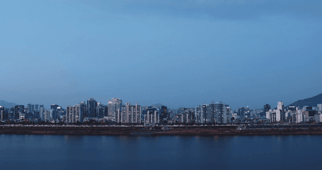 A city skyline with a river at dusk