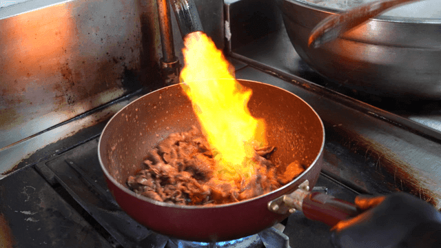 Cooking meat over direct flame in pan on stove