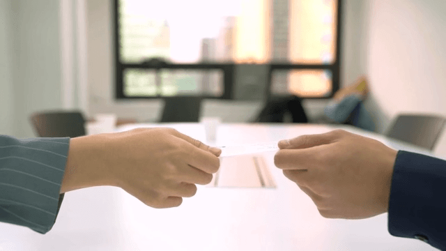 Two people exchanging business cards in an office