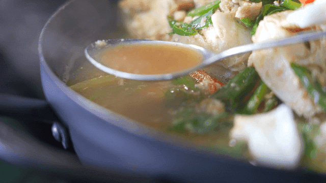 Broth lifted from crab stew with vegetables by spoon