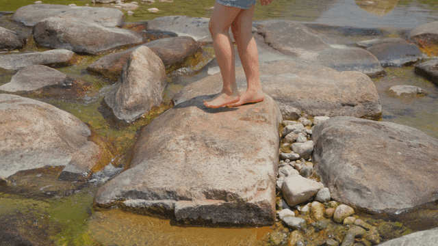 개울에서 바위를 밟고 있는 아이