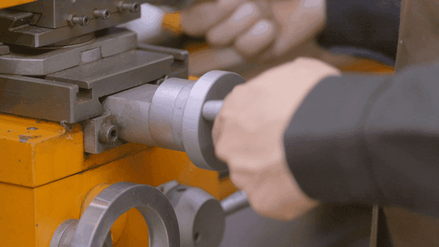 Hands operating metal lathe in workshop